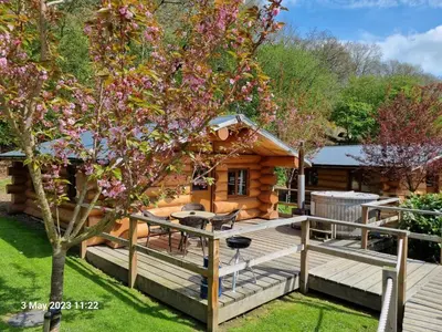 a log cabin with a deck and a tree at Mountain Edge Resort Lodge 3 with Hot Tub in Church Stretton