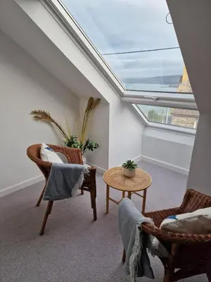 a attic room with a skylight and chairs and a table at Polruan - stunning central NQ house - dog friendly in New Quay