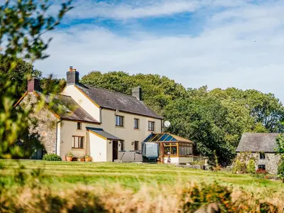 a large white house with a greenhouse in a field at 5 Bed in Aberystwyth oc-58889 in Llanrhystyd