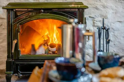 a stove with a fire inside of it at Pandy Farmhouse - Panoramic mountain views within Snowdonia's National Park - 4x4 Only in Dolgellau