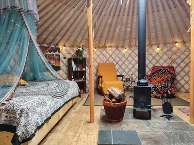 a bedroom with a bed and a stove in a yurt at Traditional Mongolian Yurt - Panoramic Mountain Retreat - 4x4 only in Dolgellau
