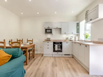 a kitchen and dining room with white cabinets and a table at The Barrels at Leintwardine in Leintwardine