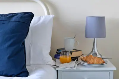 a bed with a table with a lamp and a plate of food at Finest Retreats - 37 Bro Enddwyn in Dyffryn
