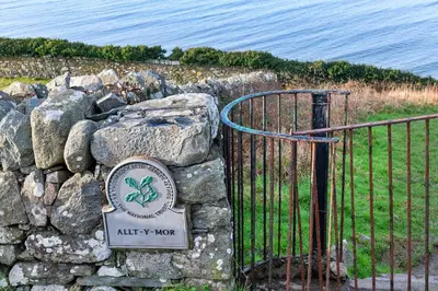a stone wall with a gate and a sign at Finest Retreats - 37 Bro Enddwyn in Dyffryn