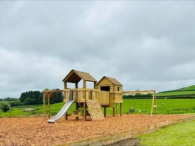 a wooden playground with a slide and a house at 1 Bed in Rhayader oc-90278 in Saint Harmon