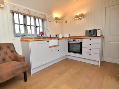 a kitchen with white cabinets and a sink and a chair at 1 Bed in Rhayader oc-90277 in Saint Harmon