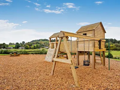 a wooden playground with a slide and a house at 1 Bed in Rhayader oc-90284 in Saint Harmon
