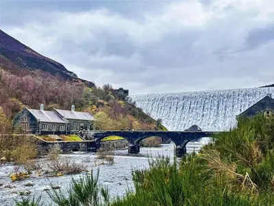 a bridge over a river with a waterfall in the background at 1 Bed in Rhayader oc-90284 in Saint Harmon