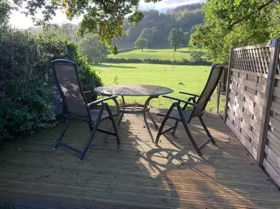 two chairs and a table on a wooden deck at Lovely peaceful 2 bed cottage in Llandderfel
