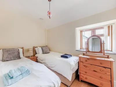 a bedroom with two beds and a mirror and a dresser at 3 Bed in Corwen oc-90459 in Corwen