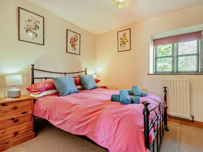 a bedroom with a large bed with pink sheets and blue pillows at 4 Bed in Painscastle 90375 in Builth Wells