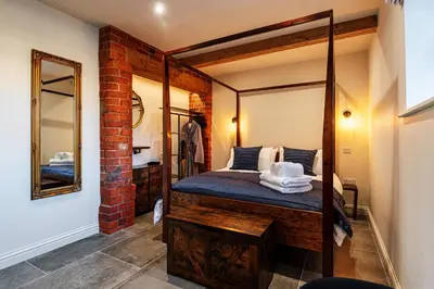 a bedroom with a four poster bed and a mirror at Pigeon House - Unique Barn with private garden, hot tub and wood burner in Shrewsbury