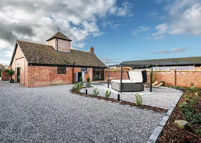 a brick building with a couch in a courtyard at Pigeon House - Unique Barn with private garden, hot tub and wood burner in Shrewsbury