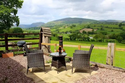 a table and chairs with a view of a field at The Retreat in Llanrhaeadr-ym-Mochnant
