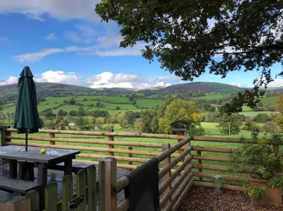 a wooden fence with a table and an umbrella at The Retreat in Llanrhaeadr-ym-Mochnant