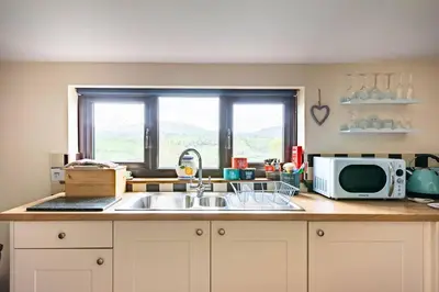 a kitchen counter with a sink and a microwave at The Retreat in Llanrhaeadr-ym-Mochnant
