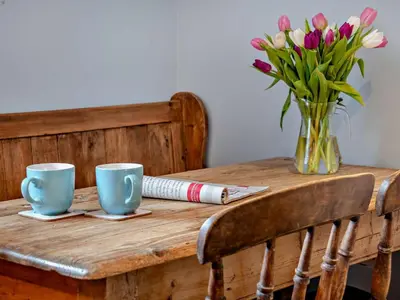 a wooden table with two cups and a vase of flowers at 2 Bed in Brecon oc-91085 in Llangorse