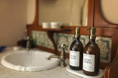 two bottles of wine sitting on a bathroom sink at Romantic Country Cottage with log burner, garden patio, outdoor tub and country views- Brecon Beacons National Park in Llangadog