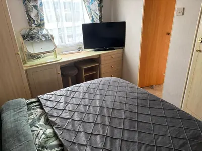 a bedroom with a bed and a desk with a television at Hilltop Hideaway 2 Bed Caravan with Panoramic Town Scenery in Aberystwyth Holiday Village F8 in Aberystwyth