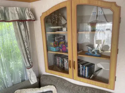 a wooden china cabinet with books in it at Hilltop Hideaway 2 Bed Caravan with Panoramic Town Scenery in Aberystwyth Holiday Village F8 in Aberystwyth