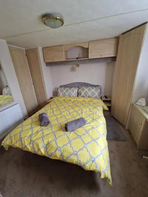 a bedroom with a bed with a yellow comforter at Hilltop Hideaway 2 Bed Caravan with Panoramic Town Scenery in Aberystwyth Holiday Village F8 in Aberystwyth