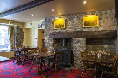 a restaurant with tables and a stone fireplace at The Kings Head Inn in Llandovery