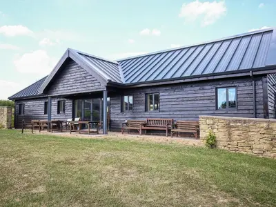 a wooden house with benches in front of it at Finest Retreats - The Walton in Onibury