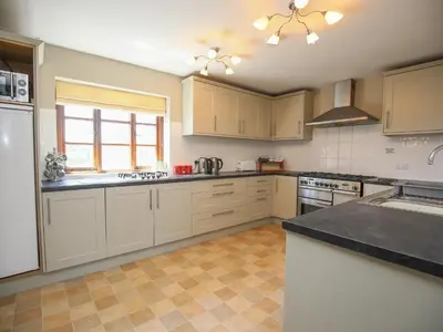 a large kitchen with white cabinets and a window at Finest Retreats - The Walton in Onibury