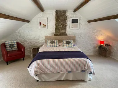 a bedroom with a bed and a red chair at No 2 Dolheulog Aberaeron in Aberaeron
