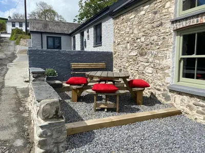 a picnic table and two red cushioned benches in front of a building at No 2 Dolheulog Aberaeron in Aberaeron