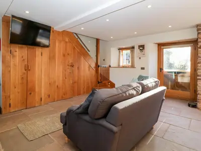 a living room with a couch and a flat screen tv at Barn Cottage in Leominster