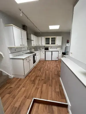 a large kitchen with white cabinets and wooden floors at Beech Cottage with Clun Castle View in Clun