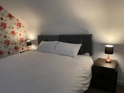 a bedroom with a large white bed with two lamps at Beech Cottage with Clun Castle View in Clun