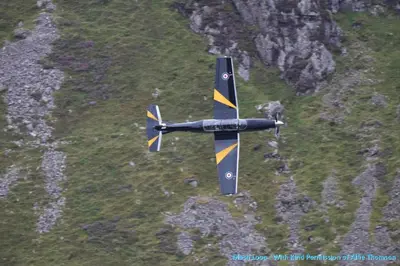 a small black and yellow plane flying over a mountain at 2 Rhys Terrace in Machynlleth