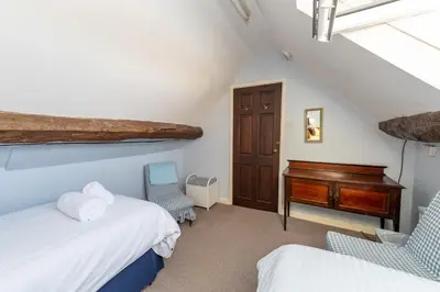 a attic bedroom with two beds and a desk at Toad Hall in Ludlow