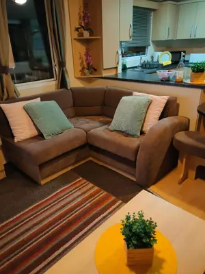 a living room with a brown couch and a table at M&C Caravan Hire Sunnysands in Barmouth