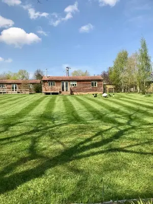 a large grass field with a house in the background at Leverets - Squirrel Lane Lodges Ludlow in Ludlow