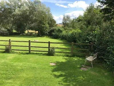 a bench sitting in a yard next to a fence at The Nut House - Squirrel Lane Lodges Ludlow in Ludlow