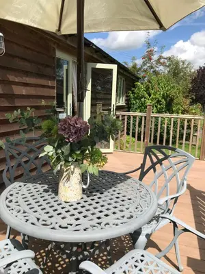 a table with a vase of flowers on a patio at The Nut House - Squirrel Lane Lodges Ludlow in Ludlow