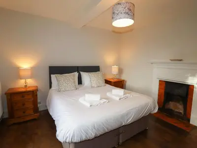 a bedroom with a large white bed with a fireplace at Wayside House in Craven Arms