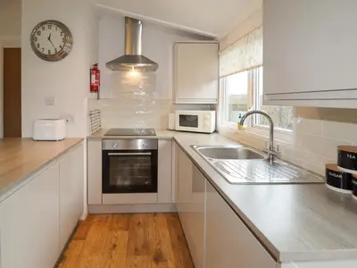 a kitchen with a sink and a clock on the wall at Wayside Lodge in Craven Arms