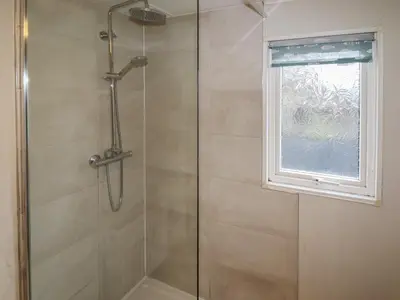 a shower with a glass door and a window at Wayside Lodge in Craven Arms