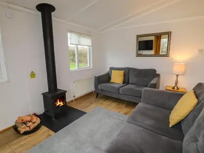 a living room with a couch and a stove at Wayside Lodge in Craven Arms