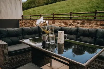 a table with glasses and a couch on a patio at Luxury 5-Bed Farmhouse - Sleeps 8 & Hot Tub in Brecon