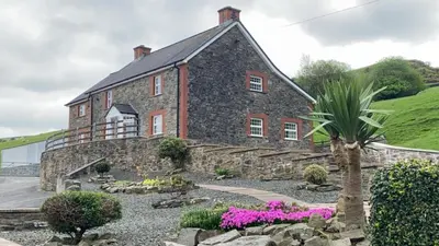 a large stone house with a palm tree in front of it at Luxury 5-Bed Farmhouse - Sleeps 8 & Hot Tub in Brecon