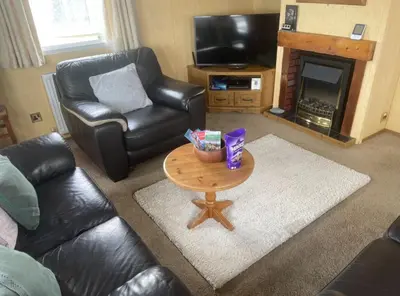 a living room with a coffee table in front of a fireplace at Spacious Luxury Escape with Sea Views and Pet Friendly at Clarach Bay in Aberystwyth