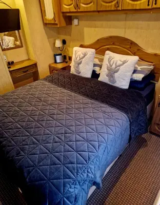 a bedroom with a large blue bed with white pillows at Spacious Luxury Escape with Sea Views and Pet Friendly at Clarach Bay in Aberystwyth