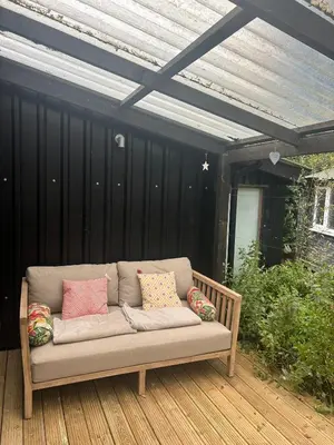 a couch sitting on a deck with pillows at The Deckhouse, cabin with big deck nr Hay-on-Wye in Rhos-gôch