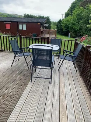 a patio with a table and chairs on a deck at Lakeside retreat - Lodge 2F caer beris holiday park - no commercial vehicles allowed on site in Builth Wells