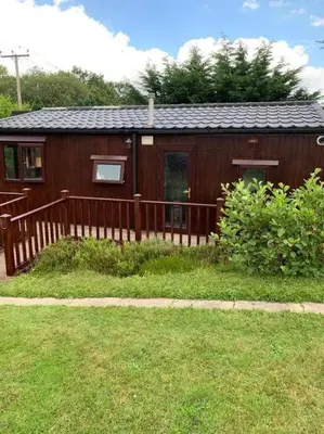 a small house with a wooden fence in the yard at Lakeside retreat - Lodge 2F caer beris holiday park - no commercial vehicles allowed on site in Builth Wells